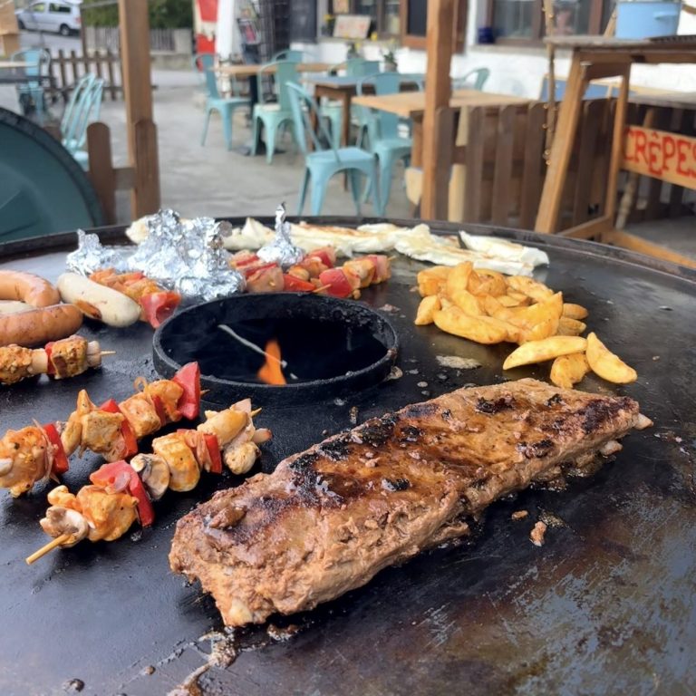 Feuerplatte-Grillen-Gruppe-Flintsbach-Rosenheim Gesellige Gruppe beim BBQ an der Feuerplatte im Garten des Hotels in Flintsbach – ideal für Teamevents und Aktivurlauber